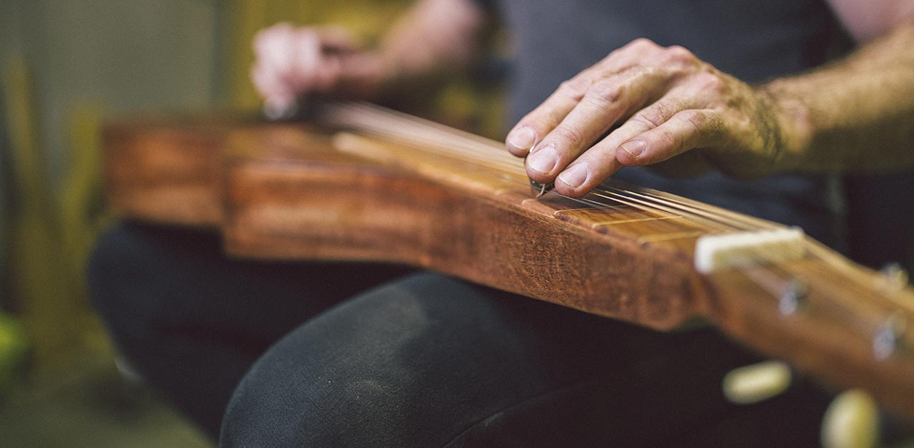 Close up of person playing a lap steel Weissenborn guitar