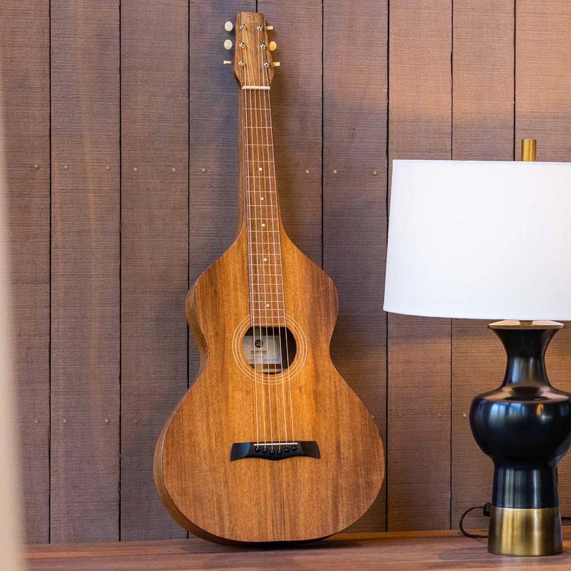 Style 1 Weissenborn Guitar by Richard Wilson against a timber wall with a black lamp