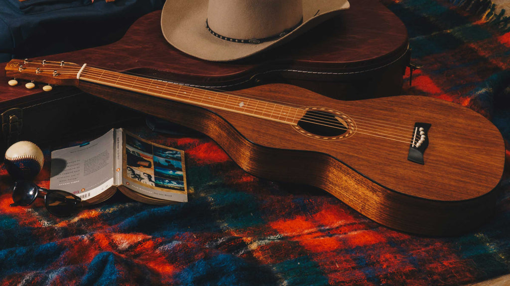 Style 2 Weissenborn Guitar by Richard Wilson on a red picnic rug with an open book and a cowboy hat